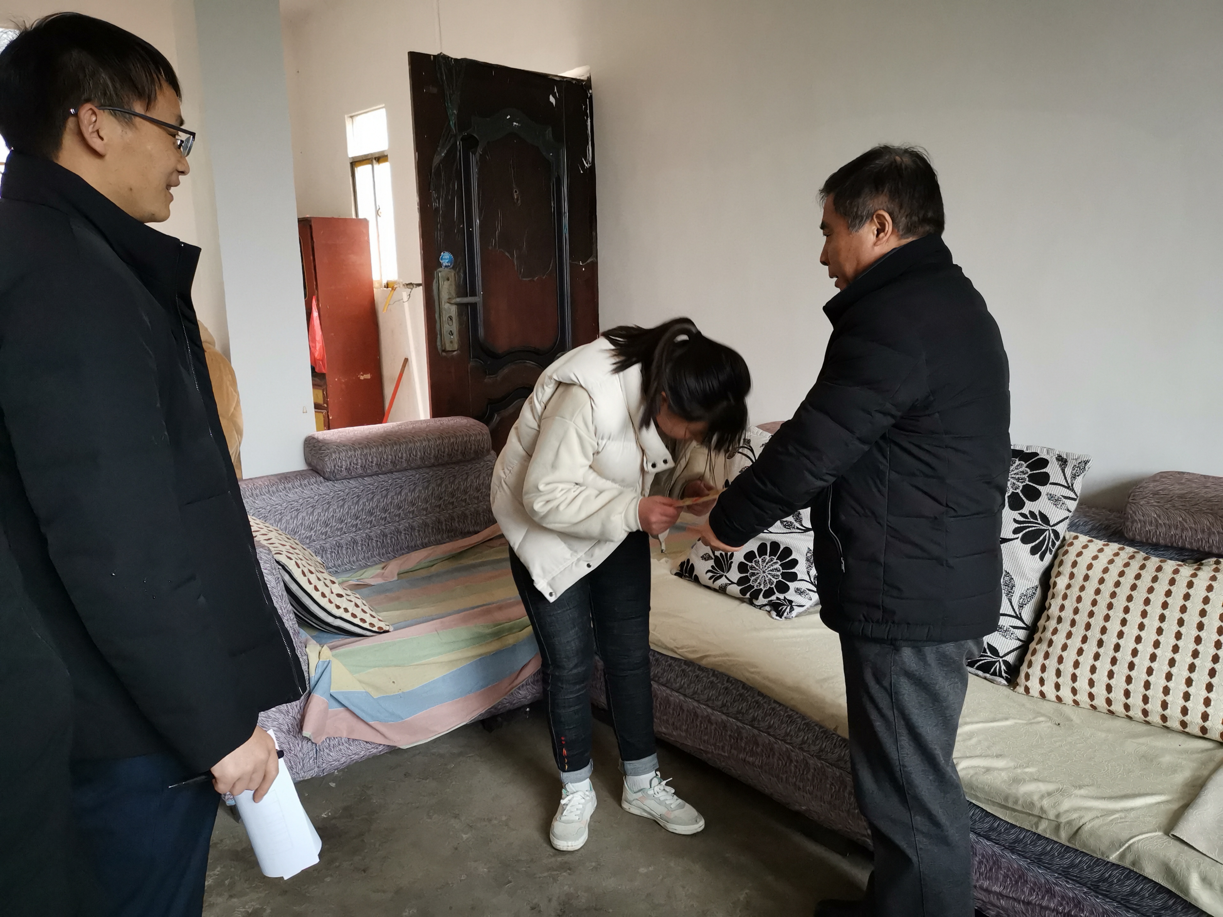 贫困户刘奇敏（中）才上高二，接过贵州省地矿局副巡视员石平（右一）送上的慰问金，小姑娘深深地鞠了一躬（林小会摄）
