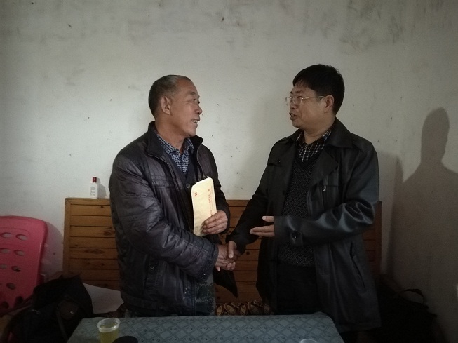 图为该队党委书记将慰问金送到退休职工手中.jpg