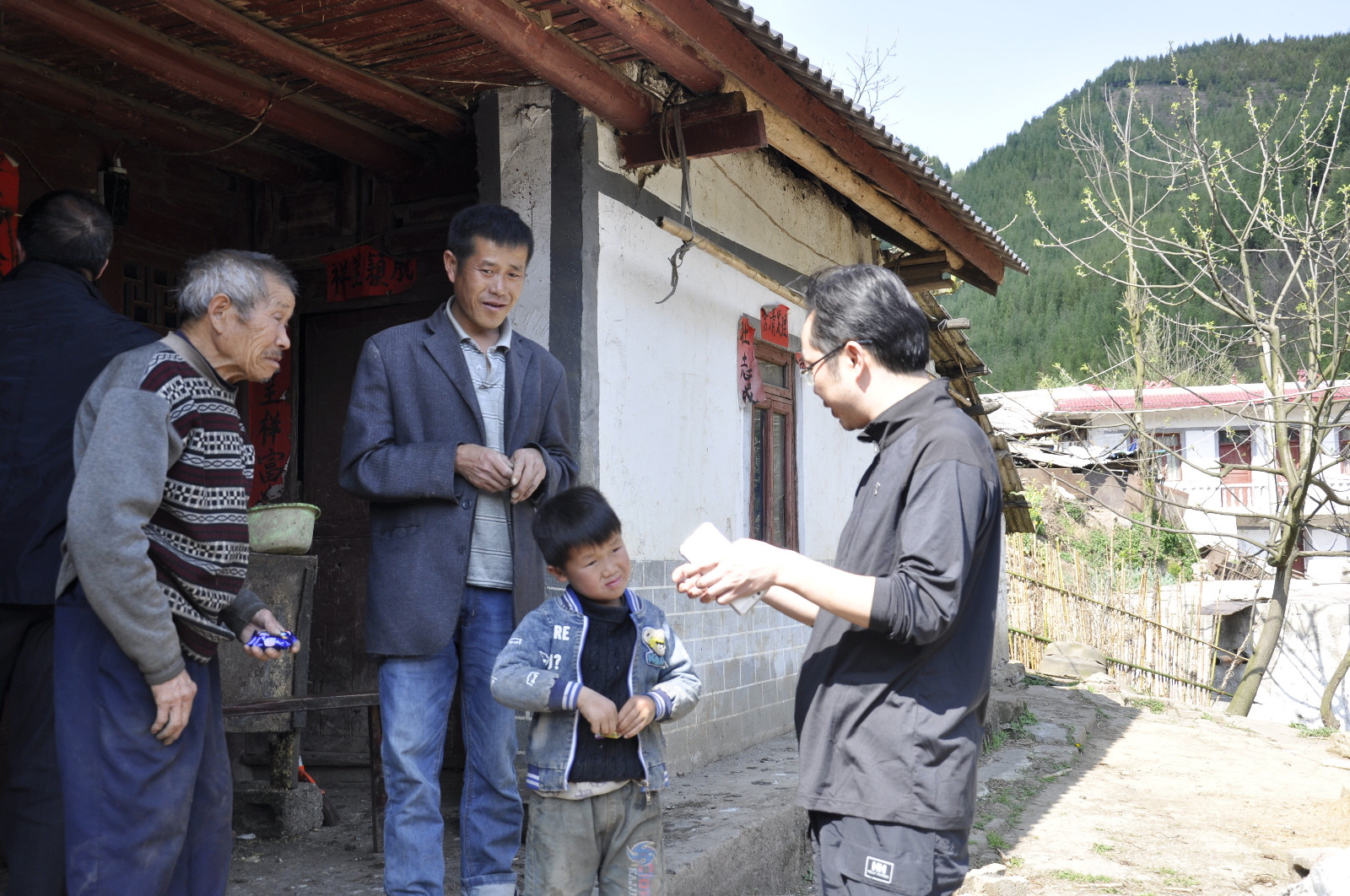 在马落菁村，局纪委书记蒙忠（右一）与村民金庭朝（左一）祖孙三代交流（林小会摄）.JPG